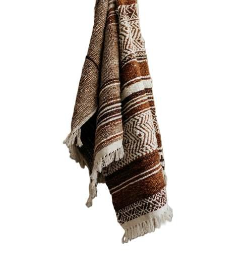 Draped woven cotton area rug featuring rust and brown tribal geometric patterns with decorative fringe.