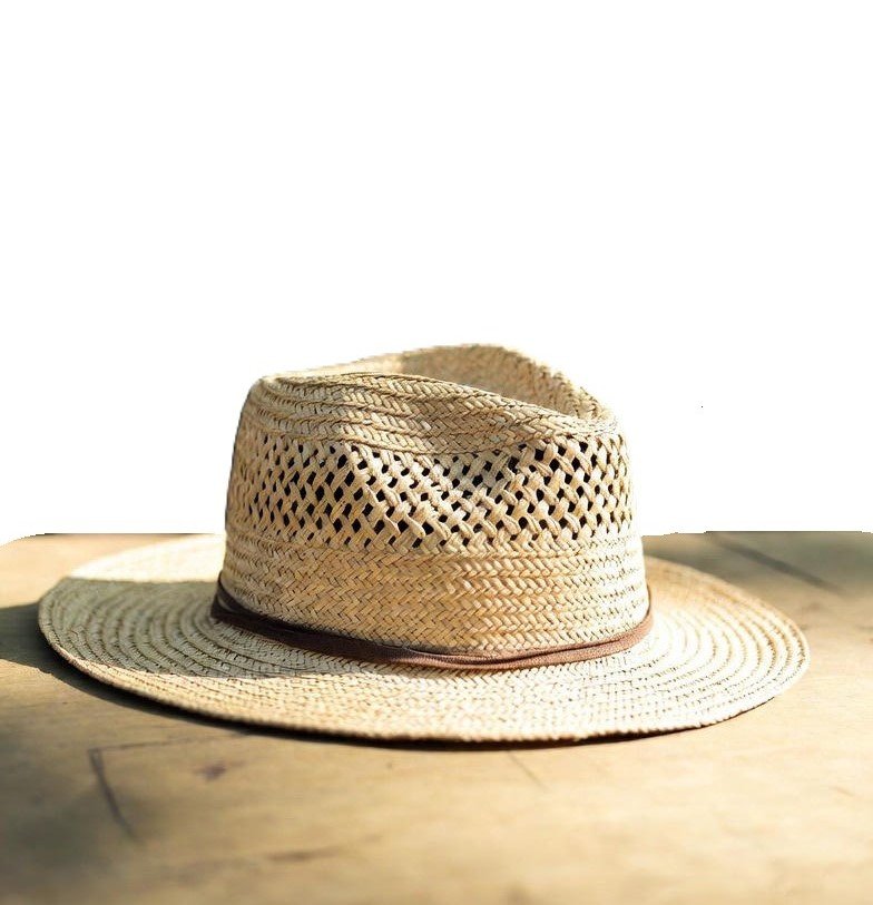 Ventilated straw hat featuring an open-weave pattern and a brown leather band, resting on a wood surface in natural sunlight.