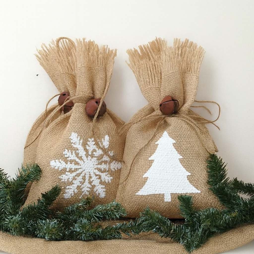 Two small Christmas gift sacks made of burlap, stenciled with a white snowflake and a Christmas tree.