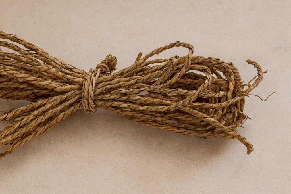 Close-up of bundled, dried seagrass rope material on a neutral floor. Natural fiber basket weaving.