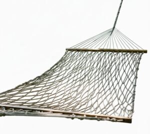 White woven rope hammock with wooden spreader bars isolated against a bright sky.