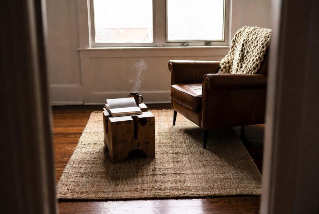 cozy reading nook featuring a leather armchair and coffee mug on a natural handmade area rugs.