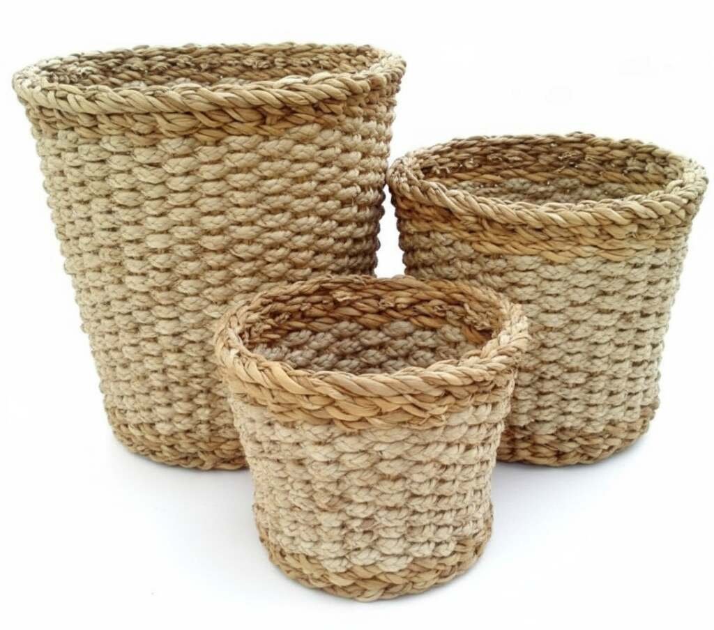 set of three cylindrical handmade seagrass planters with decorative woven rims in natural tones.