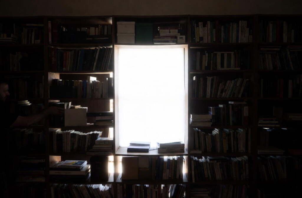 Dark bookshelf placed directly in front of a window, blocking natural light and making the room feel dim and heavy