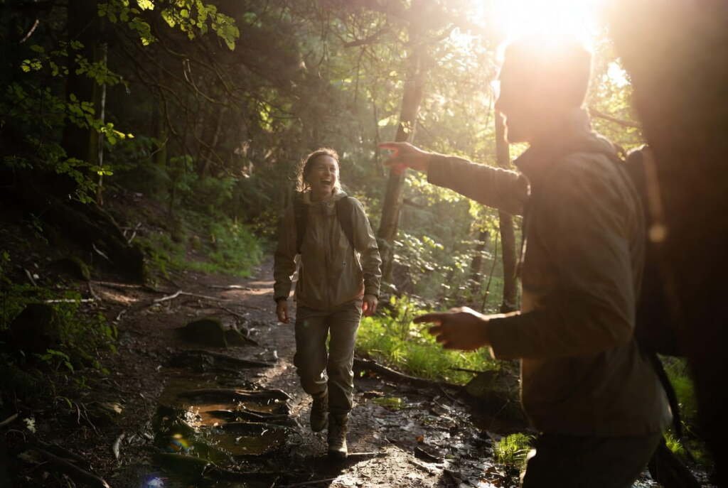 two friends laughing on a muddy forest trail at golden hour enjoying an eco-friendly experience gift nature walk